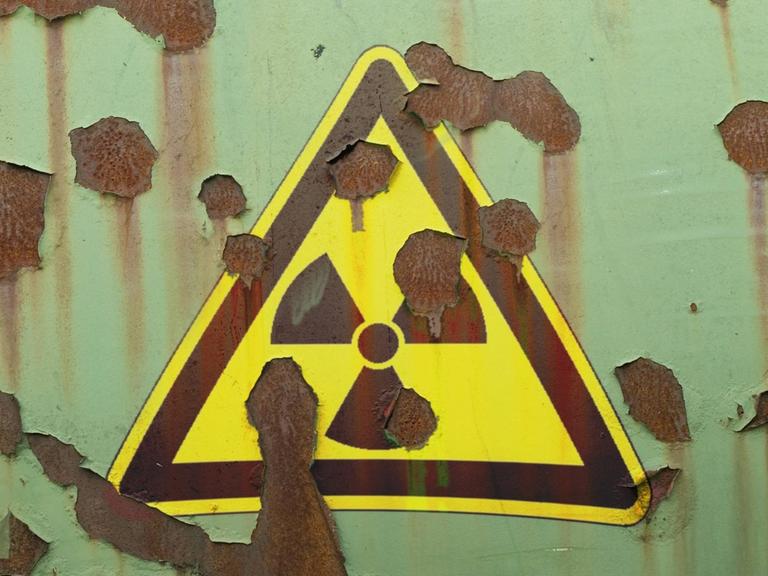 Abblätterndes Hinweisschild auf Radioaktivität an einer Mauer