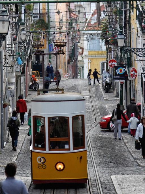 Die Standseilbahn "Ascensor da Bica" fährt durch eine Gasse in Lissabon.