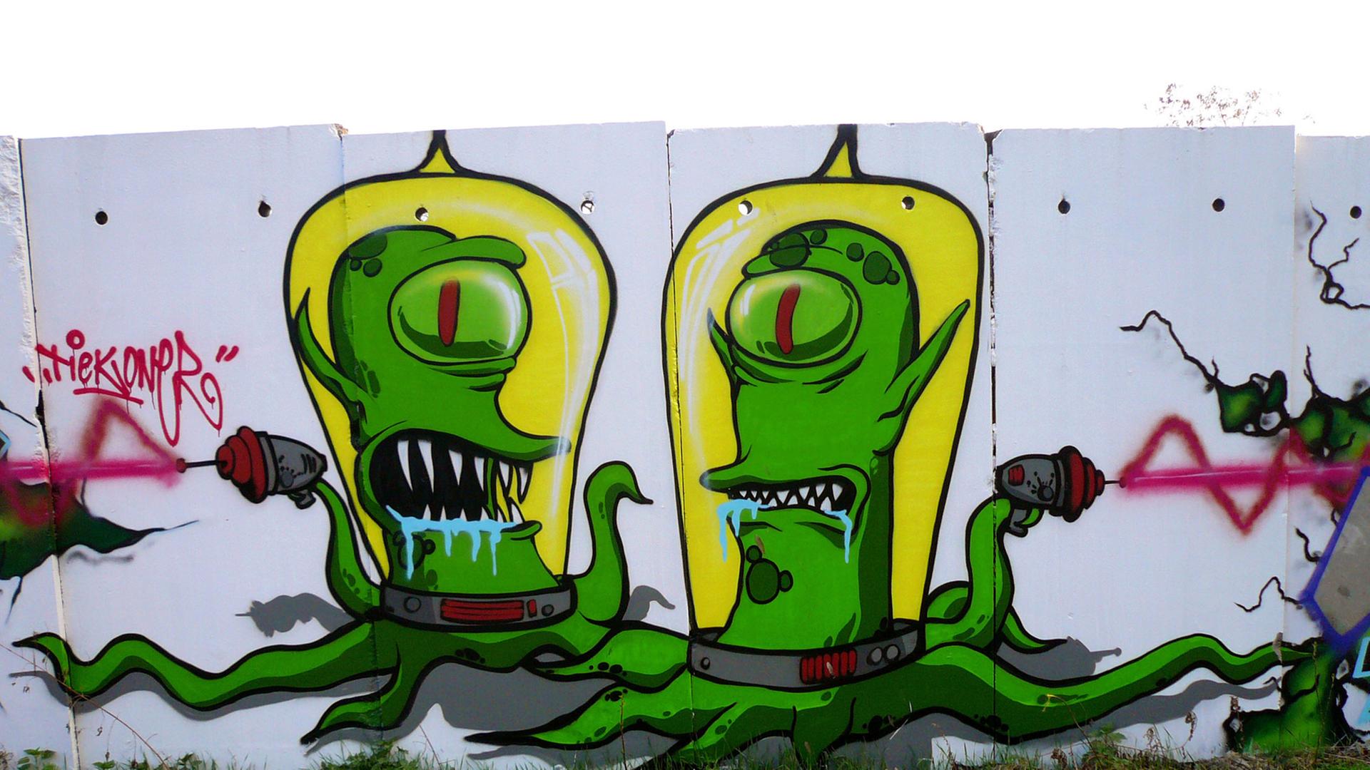Zwei Außerirdische aus der Comic-Fernsehserie "Die Simpsons" an Mauersegmenten in Berlin