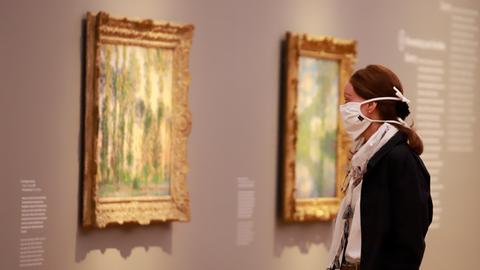 Eine Besucherin mit Mundschutz schaut auf Bilder in einer Ausstellung des Museum Barberini