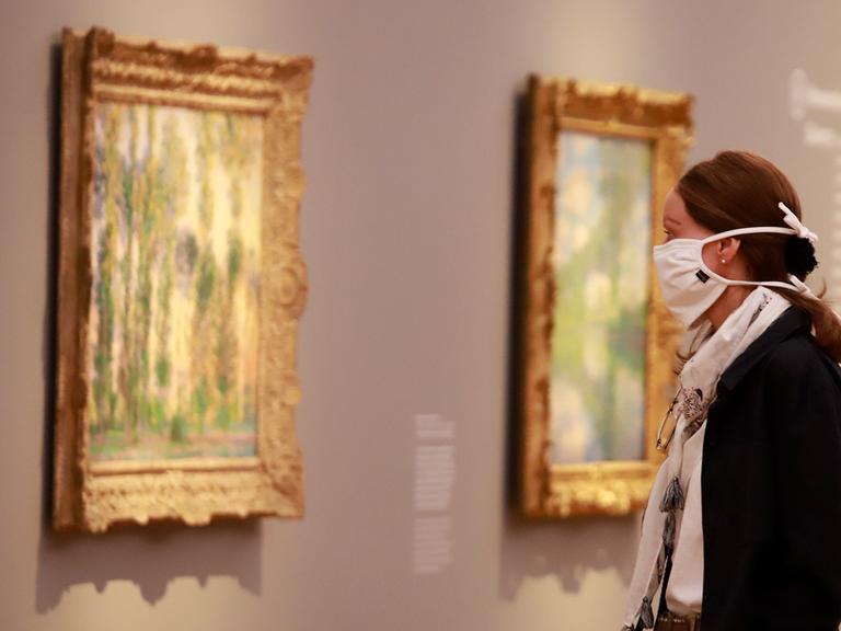 Eine Besucherin mit Mundschutz schaut auf Bilder in einer Ausstellung des Museum Barberini