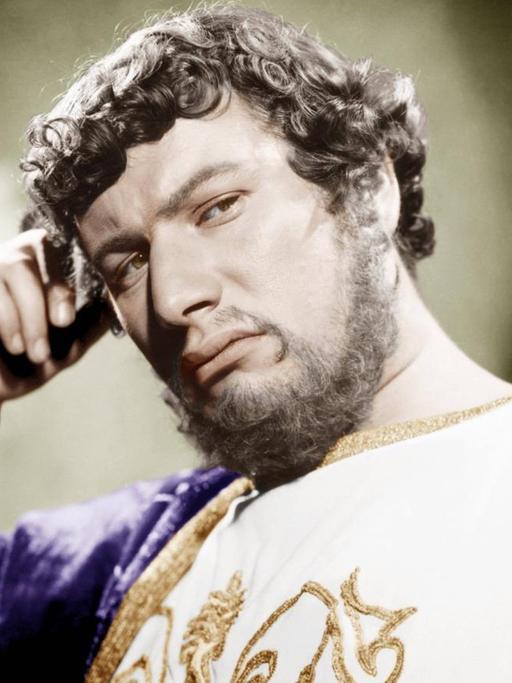Ein Film-Still zeigt den Schauspieler Peter Ustinov als Kaiser Nero in purpurnem Gold-verzierten Gewand den Kopf nachdenklich auf die rechte Hand gestützt