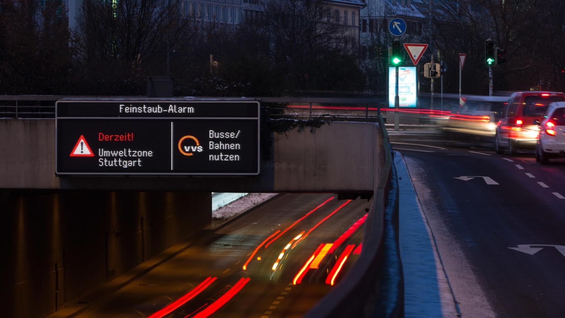 Autos fahren am 18.01.2016 in Stuttgart (Baden-Württemberg) durch die Innenstadt, während auf einer Anzeige ein Feinstaub-Alarm für die Umweltzone Stuttgart angezeigt und auf öffentliche Verkehrsmittel hingewiesen wird.