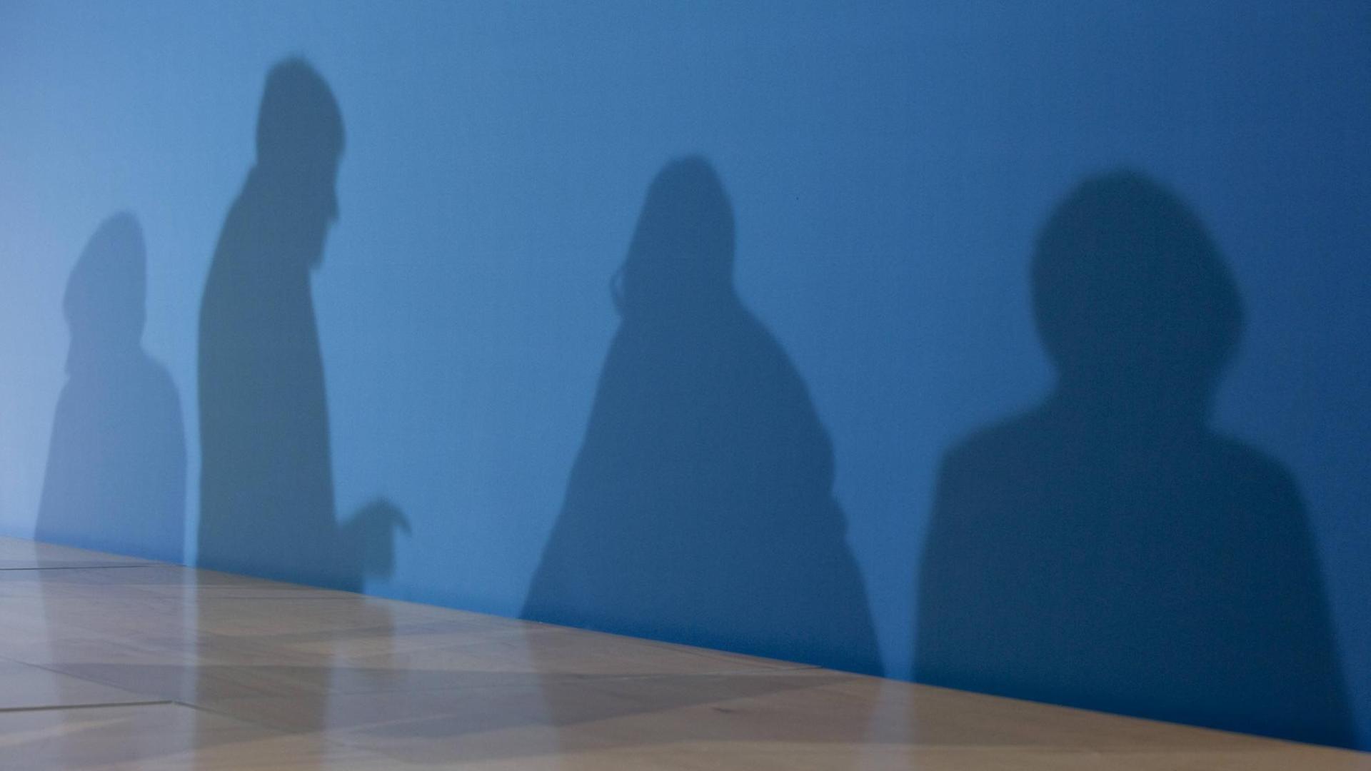 Die Schatten von Horst Seehofer, Angela Merkel und Martin Schulz auf einer blauen Wand
