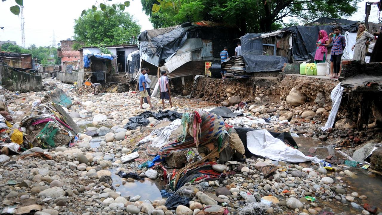 Anwohner stehen nach einer Sturzflut vor den Überresten ihrer beschädigten Häuser. Starke Regenfälle haben Erdrutsche ausgelöst und sind eine Bedrohung für viele Dörfer in der Nähe von Flüssen in der Region Jammu. 