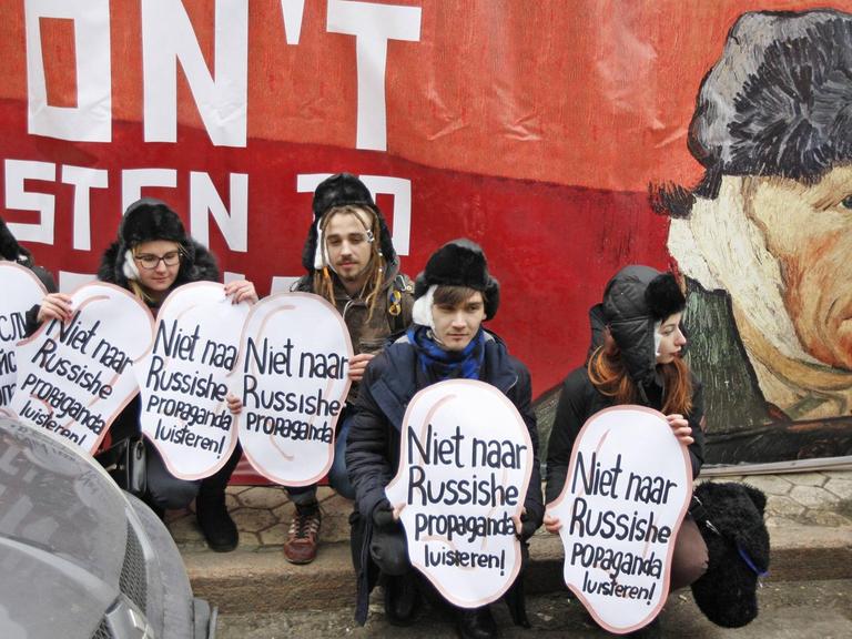 Ukrainische Aktivisten halten vor einem Porträt des niederländischen Malers Vincent van Gogh Plakate in Ohrform hoch mit der Aufschrift "Nicht auf russische Propaganda hören."