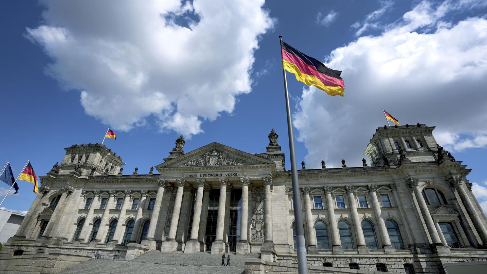 Das Gebäude des Bundestages. Davor weht die deutsche Flagge.