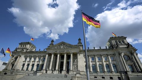 Das Gebäude des Bundestages. Davor weht die deutsche Flagge.