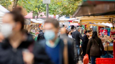 Menschen tragen Mund-Nasen-Bedeckungen und gehen in Berlin-Kreuzberg über den Markt am Maybachufer.