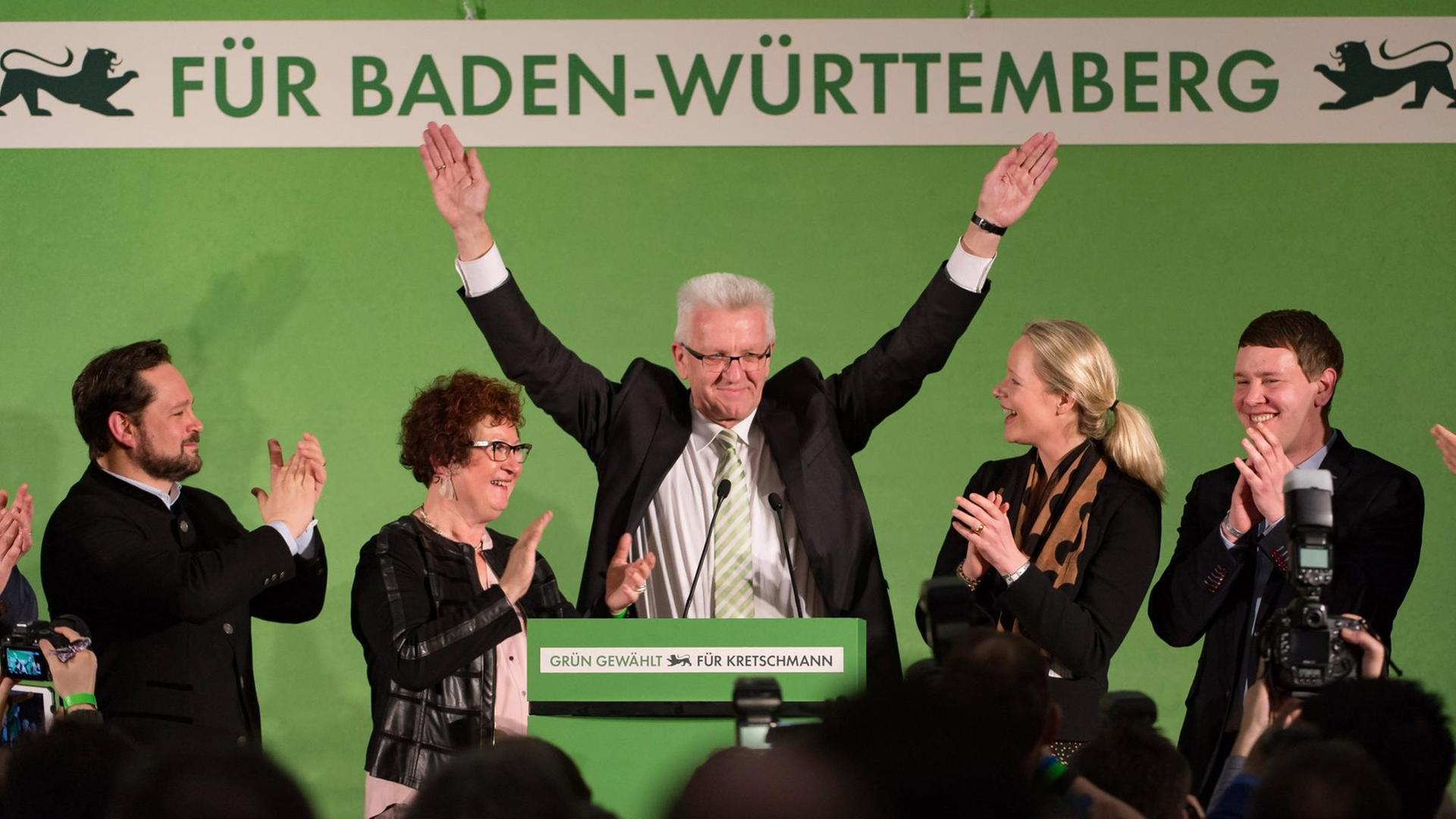 Winfried Kretschmann und seine Frau Gerlinde stehen auf einem Podium und lassen sich feiern