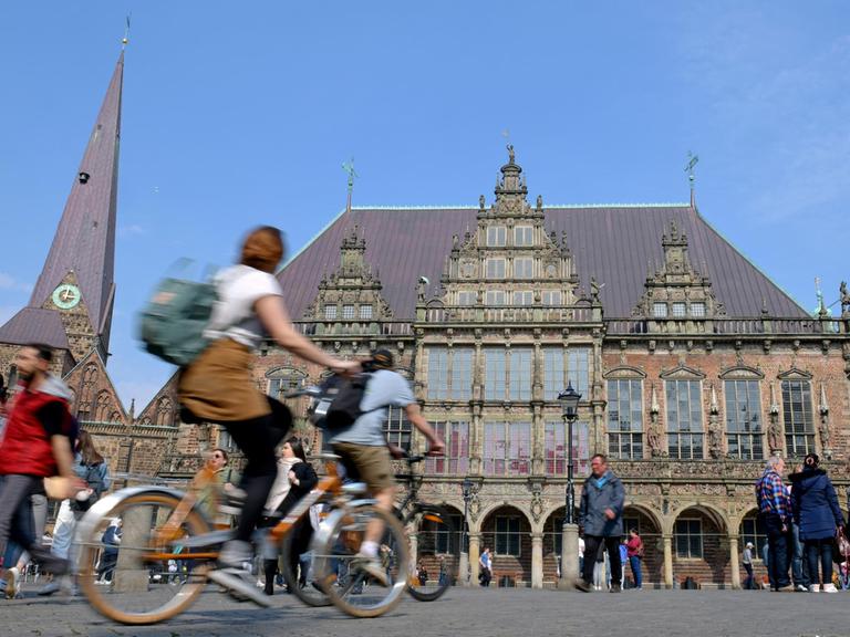 Zwei Radfahrer fahren über den Bremer Marktplatz, im Hintergrund das Rathaus.