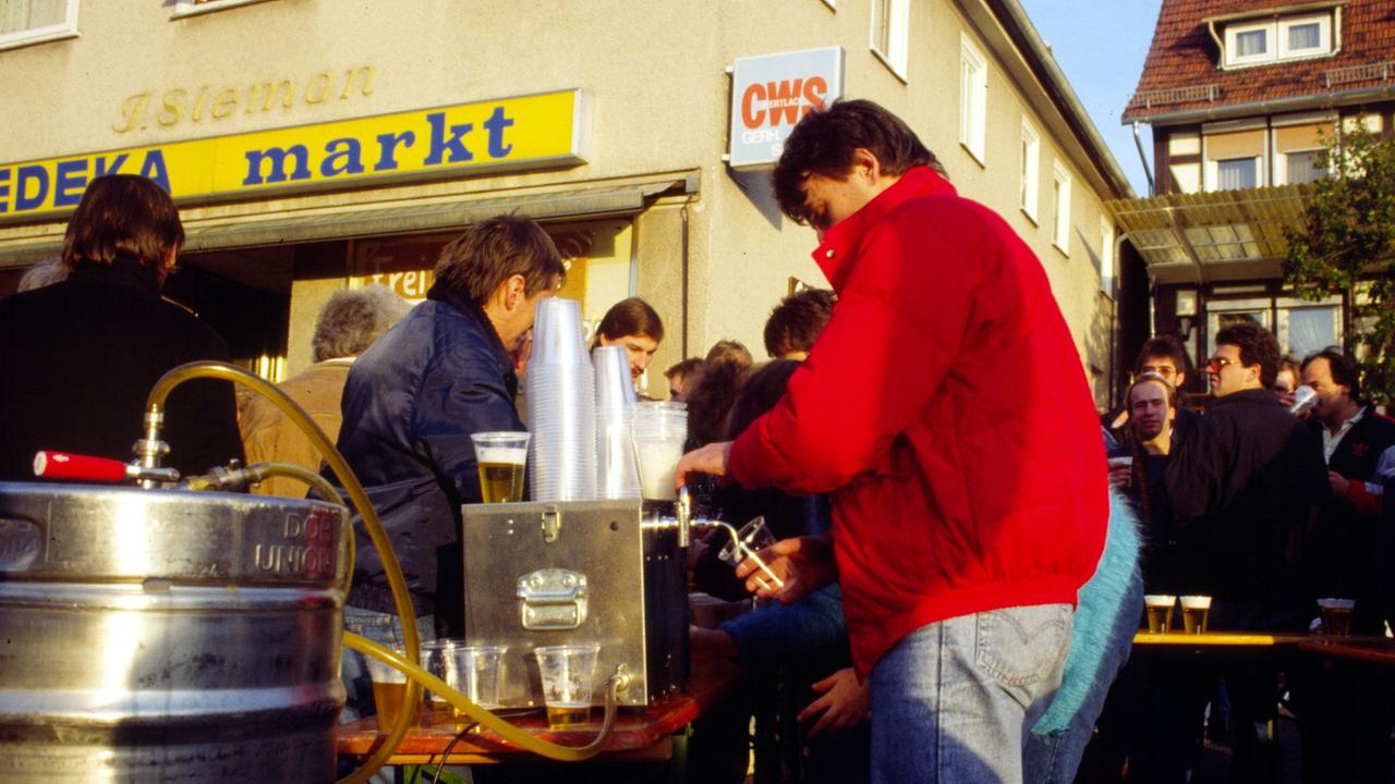 Auf einer Dorfstraße wird Bier ausgeschenkt.