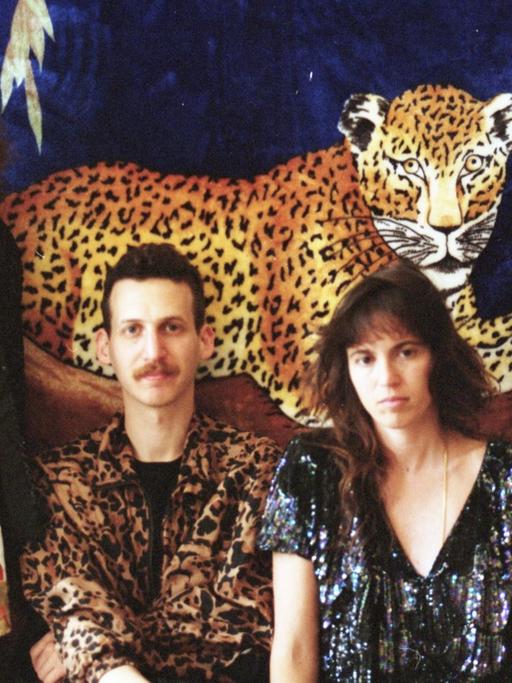 Zwei Frauen und zwei Männer stehen vor einem Gemälde eines Leoparden.