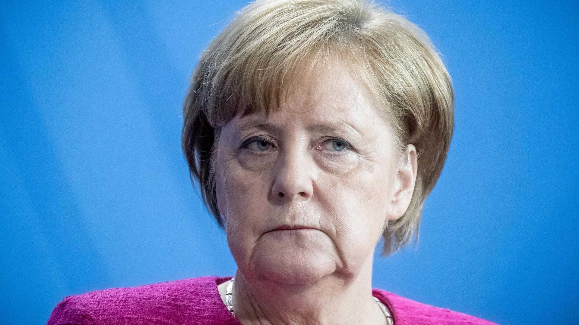 Bundeskanzlerin Angela Merkel in Nahaufnahme vor blauem Hintergrund