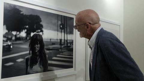 Magnum-Fotograf David Alan Harvey schaut sich bei einer Ausstellung eines seiner Fotos genauer an.