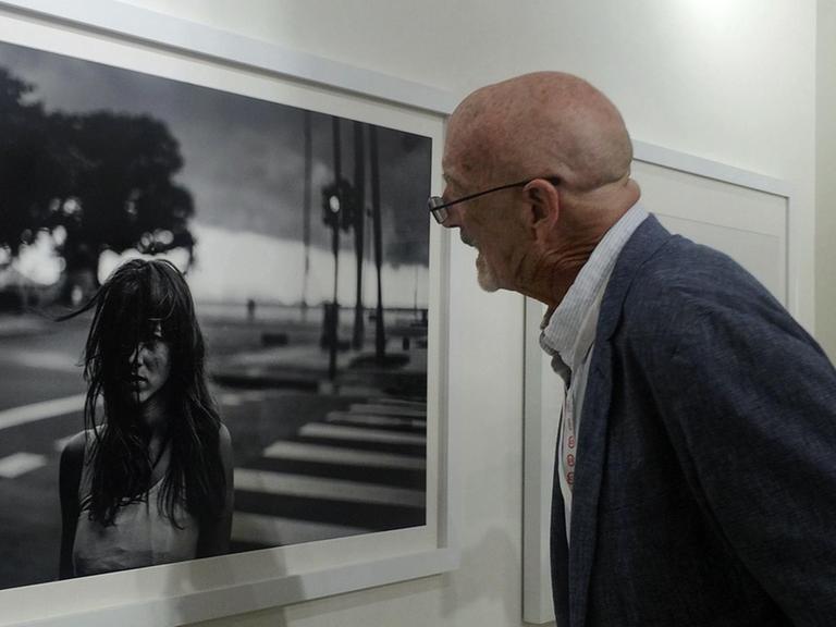 Magnum-Fotograf David Alan Harvey schaut sich bei einer Ausstellung eines seiner Fotos genauer an.