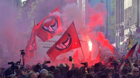 Viele Menschen stehen während einer Kundgebung am 1. Mai 2018 in Berlin in einer Straße. Es werden mehrere Fahnen mit dem Logo der Antifa hochgehalten.