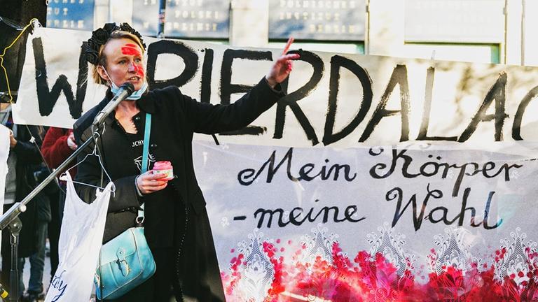Die Aktionskünstlerin Anna Krenz in Berlin vor einem Transparent mit der Aufschrift "Mein Körper - meine Wahl".