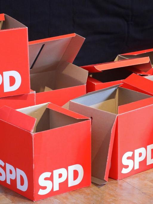 Leere Stimmzettel-Boxen stehen beim SPD-Landesparteitag vor der Bühne.