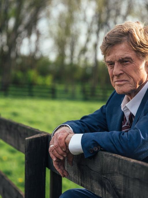 Der Schauspieler Robert Redford steht an einem Zaun und schaut in die Ferne.