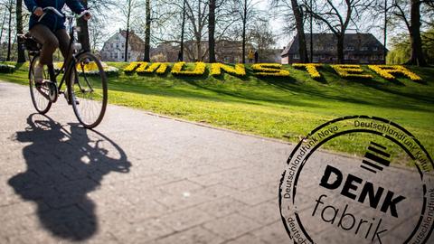 Eine Radfahrerin fährt auf der Promenade entlang, im Hintergrund steht der Schriftzug «Münster», aus Blumen gefertigt. Der ADFC-Fahrradklima-Test 2018 ist eine Befragung mit dem Ziel der vergleichbaren Erfassung von Radfahrbedingungen in Staädten und Gemeinden. Die Datenerhebung zum ADFC-Fahrradklima-Test 2018 erfolgte vom 1.9.2018 bis zum 30.11.2018. Deutschlandweit wurden Radfahrer gebeten, ihre Einschätzung zum Radverkehr in ihrer Stadt abzugeben. Mit Denkfabrik-Stempel.