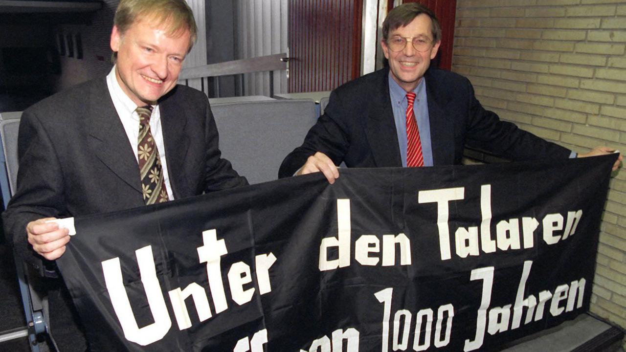 Am 8.11.1997 erinnerten Detlev Albers (links), damals Jura-Professor und Vorsitzender der Bremer SPD, und Gert Hinnerk Behmler (rechts), damals Staatsrat der Hamburger Senatskanzlei, im Audimax mit dem gleichen Banner an ihre Aktion 30 Jahre zuvor.