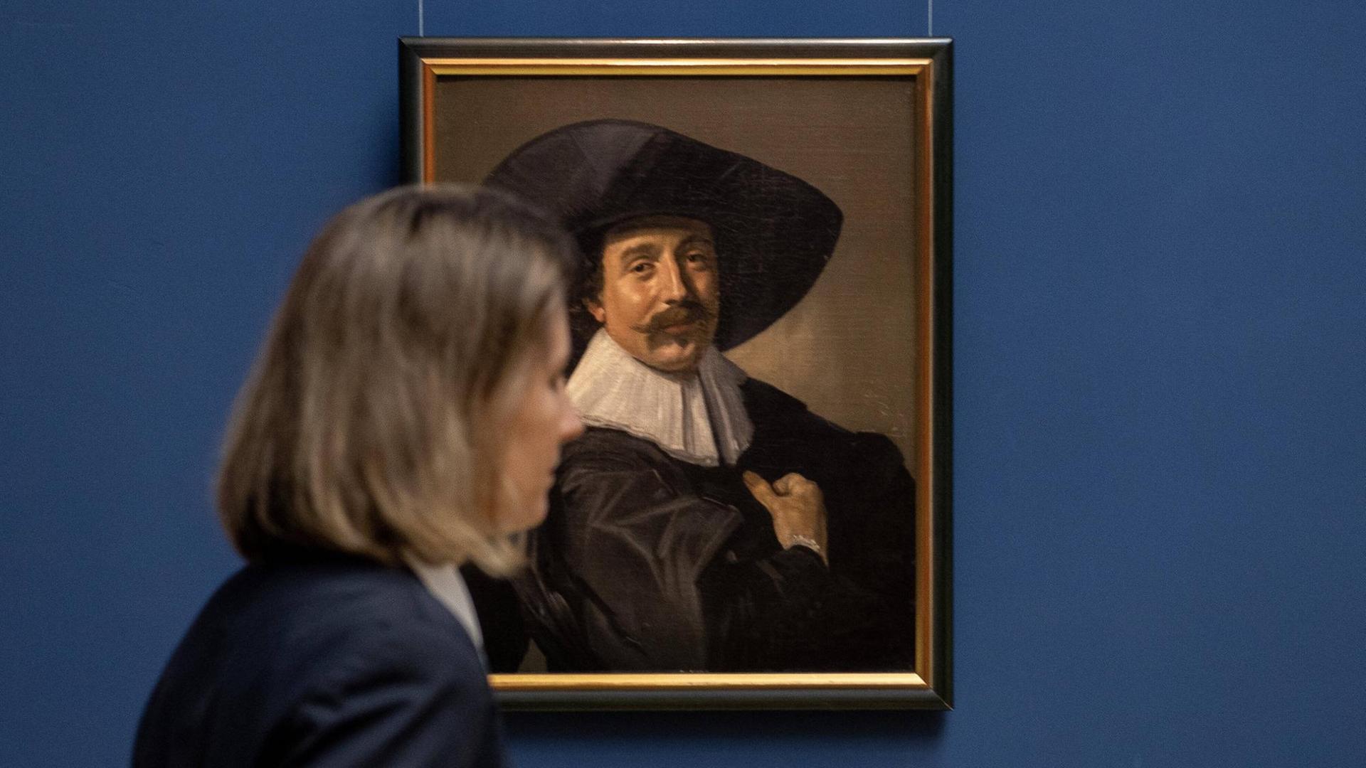 Eine Frau schaut sich das Brustbild eines unbekannten Herrn mit Hut und Handschuhen, um 1535 von Frans Hals an, das 1979 im Gothaer Kunstraub gestohlen wurde und jetzt wieder in die Stiftung Schloss Friedenstein Herzögliches Museum Gotha zurückgeführt wurde.