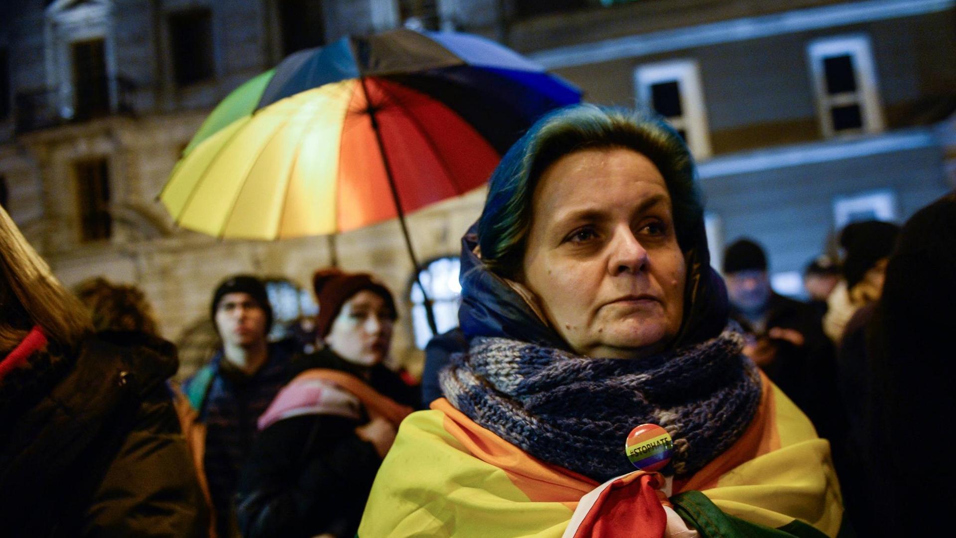 Ein Frau in Warschau hat eine Regenbogenflagge um sich gewickelt. Im Hintergrund weitere Demonstranten. Sie demonstrieren gegen LGBT-freie Zonen in Polen.