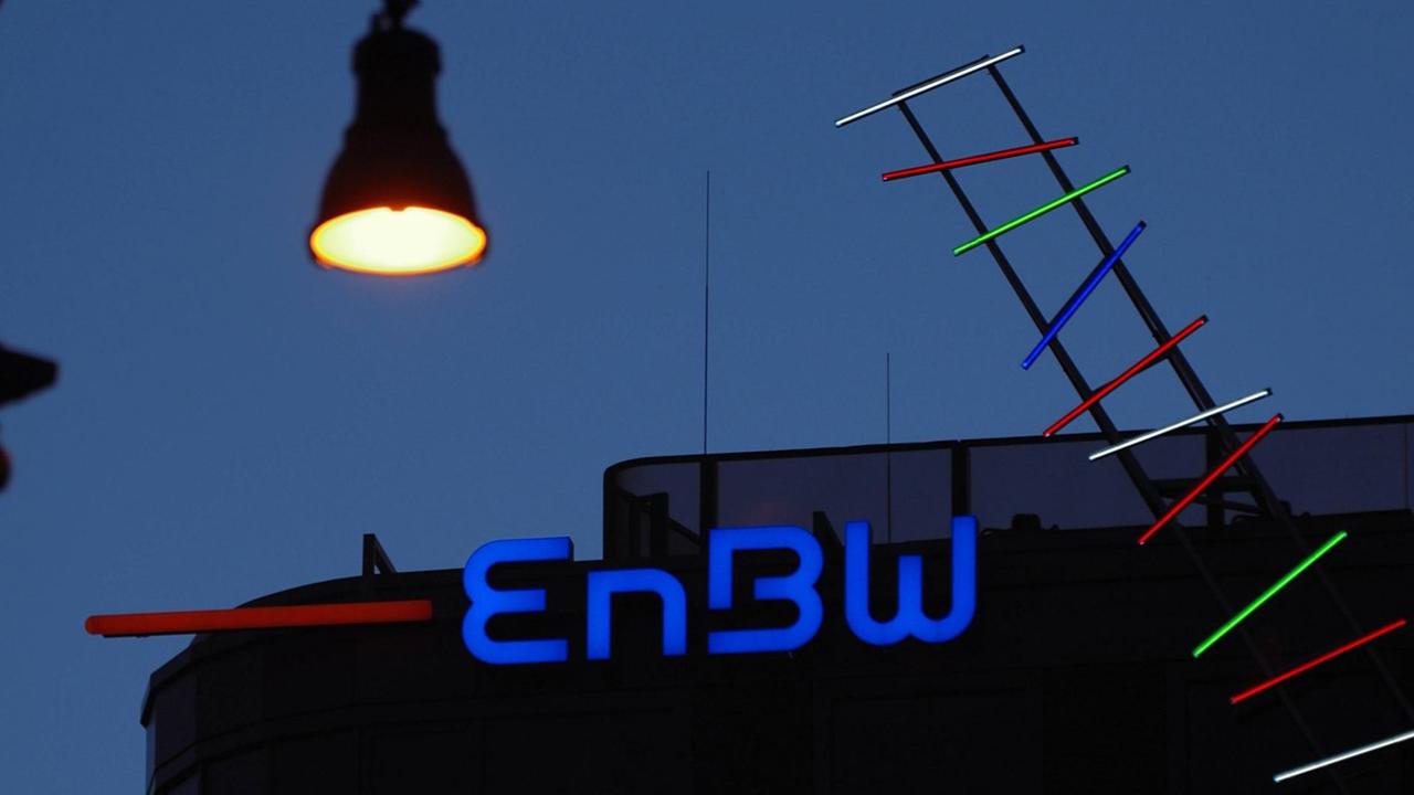 Eine Straßenlaterne über dem Logo der EnBW im abendlichen Berlin.