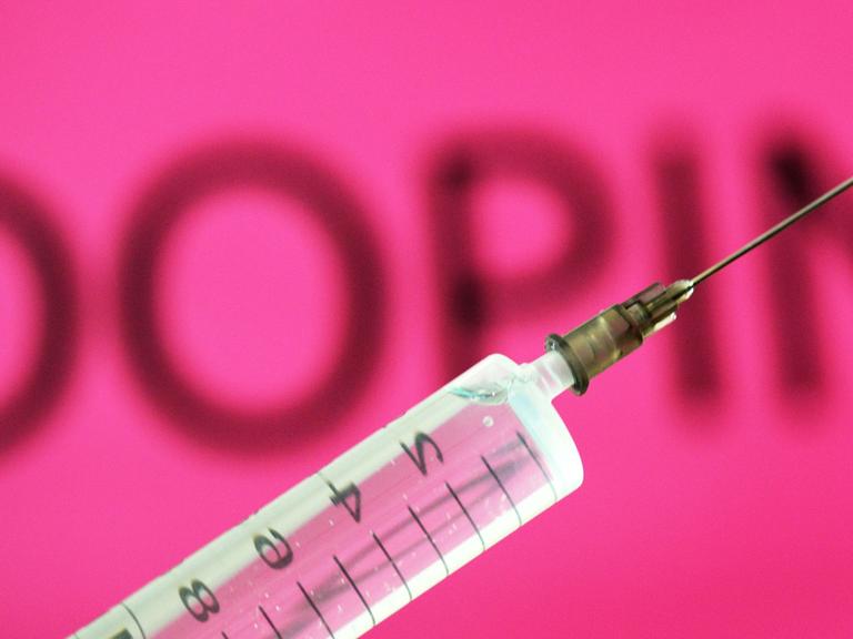Eine Spritze vor einem pinken Schild mit der Aufschrift 'Doping'
