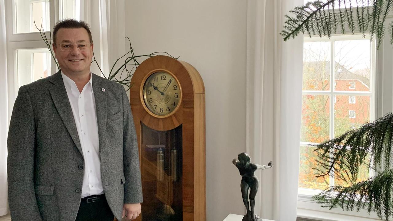 Porträt vom Sassnitzer Bürgermeister Frank Kracht  neben einer Stannduhr in seinem Büro.