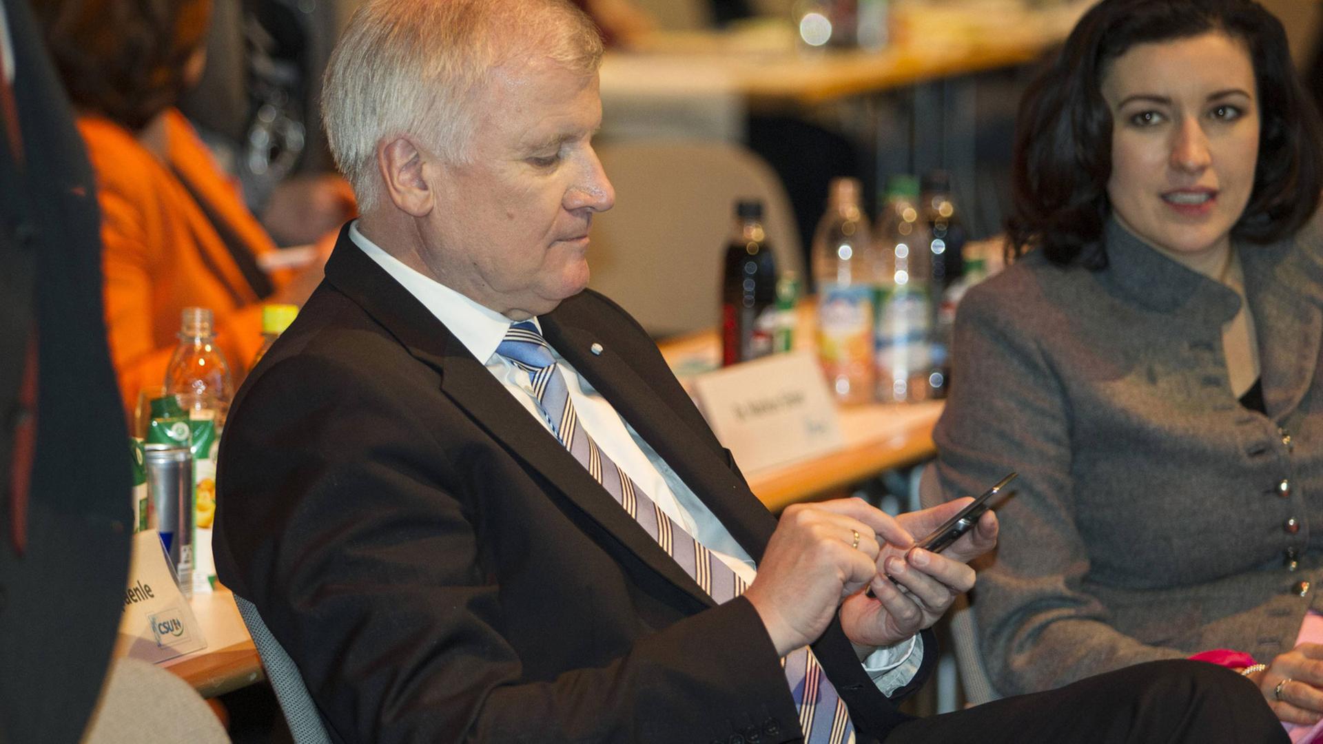 Horst Seehofer, CSU, tippt etwas in sein Smartphone.
