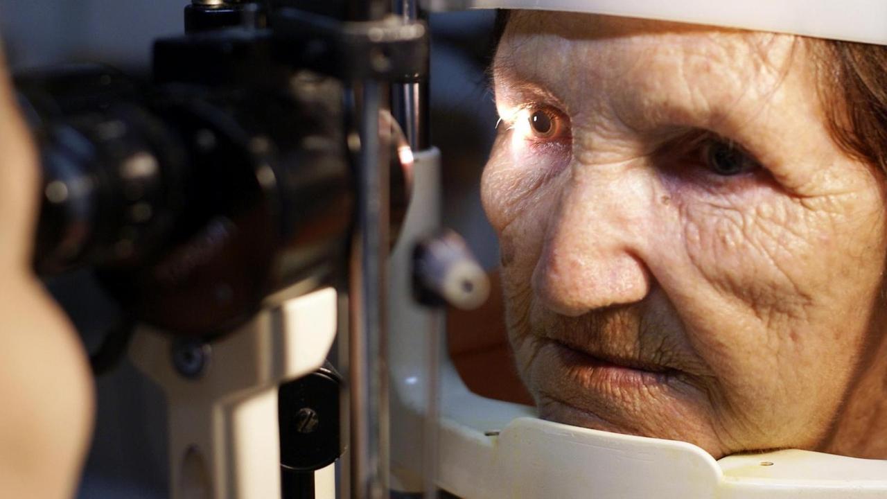 Ein Arzt leuchtet einer alten Frau in die Augen.