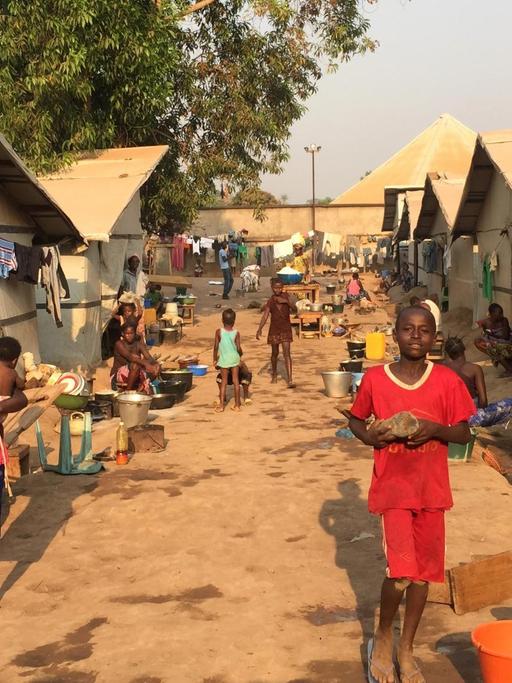 Blick in das Lager Benz-Vi in Bangui, der Hauptstadt der Zentralafrikanischen Republik, in dem auf einer Fläche von etwa zwei großen deutschen Supermärkten mehr als 2600 Binnenflüchtlinge leben. Auf unbefestigtem Boden stehen Zelte, davor mehrere Kinder und Frauen.