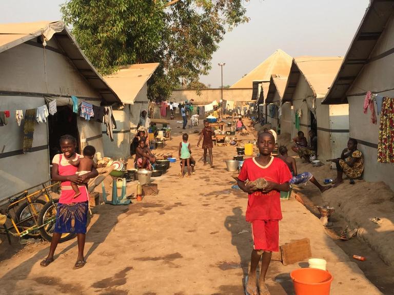 Blick in das Lager Benz-Vi in Bangui, der Hauptstadt der Zentralafrikanischen Republik, in dem auf einer Fläche von etwa zwei großen deutschen Supermärkten mehr als 2600 Binnenflüchtlinge leben. Auf unbefestigtem Boden stehen Zelte, davor mehrere Kinder und Frauen.