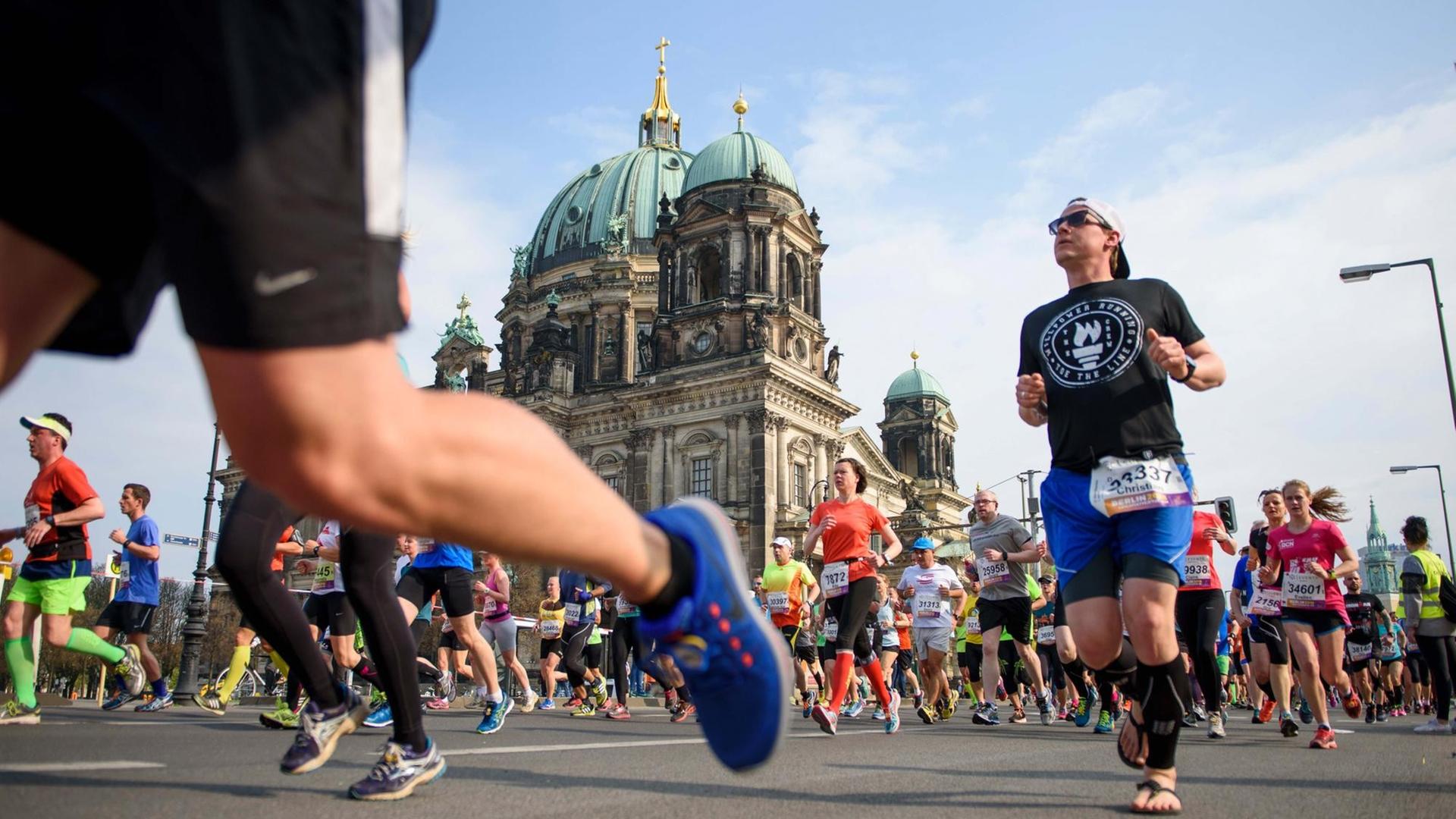 Teilnehmer laufen während des 37. Halbmarathon in Berlin am Berliner Dom vorbei.