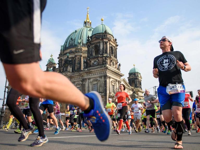 Teilnehmer laufen während des 37. Halbmarathon in Berlin am Berliner Dom vorbei.