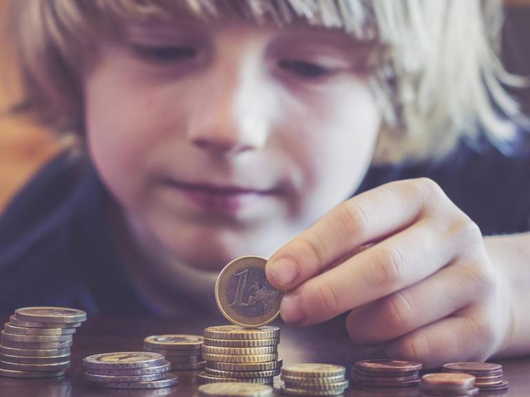 Ein Kind zählt Euromünzen.