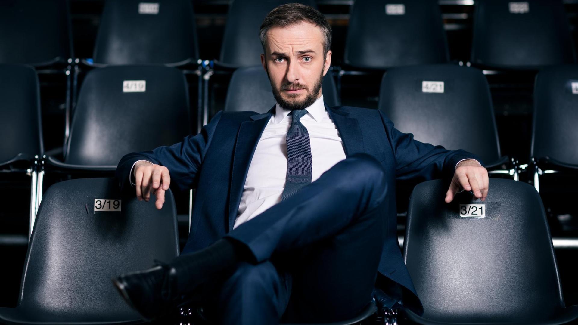 "Neo Magazin Royale": Jan Böhmermann sitzt auf einem schwarzen Stuhl. Links, rechts und hinter ihm stehen in Reihen weitere schwarze Stühle.