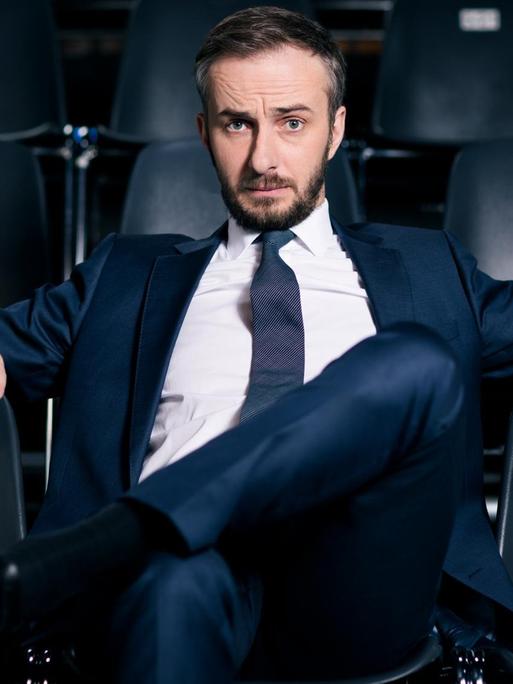 "Neo Magazin Royale": Jan Böhmermann sitzt auf einem schwarzen Stuhl. Links, rechts und hinter ihm stehen in Reihen weitere schwarze Stühle.