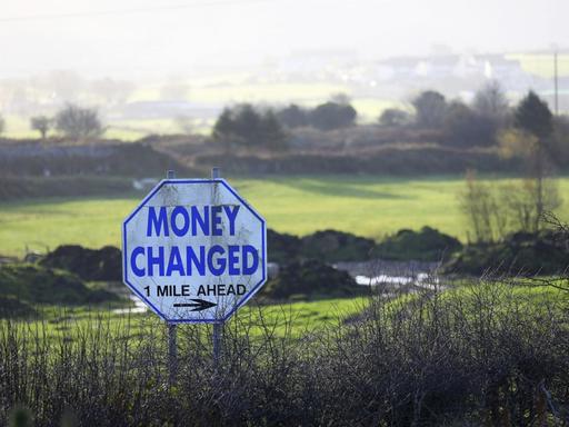 Ein Straßenschild mit der Aufschrift "Money Changed" (Geld wechseln) steht in einer Hecke an der Grenze zwischen Nordirland und der Republik Irland.