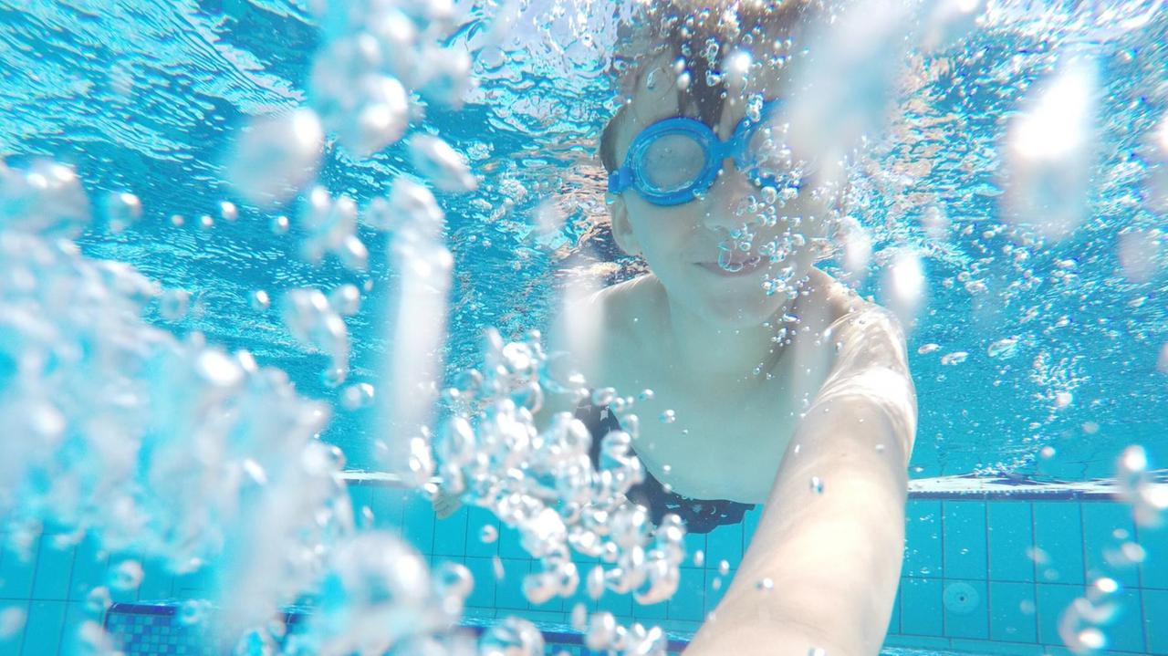 Unterwasser-Aufnahme von einem Kind beim Tauchen in einem Schwimmbad