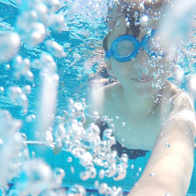 Unterwasser-Aufnahme von einem Kind beim Tauchen in einem Schwimmbad