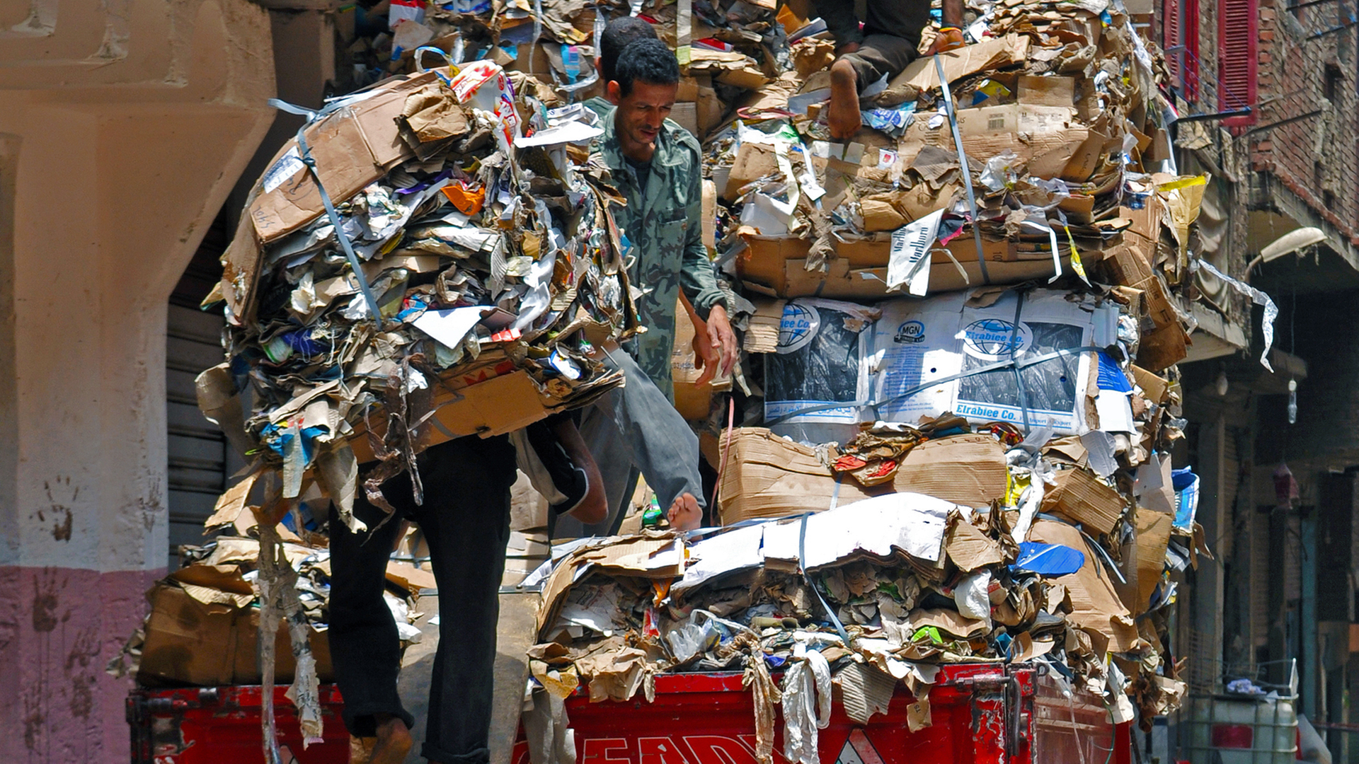 Über eine Holzplanke beladen Männer in Manshiet Nasr einen LKW mit kompaktiertem und sortiertem Altpapierabfall, aufgenommen am 21.05.2014. In Kairo wird die Müllentsorgung von rund 70000 Müllsammlern, den sogenannten Zabbaleen, gemanagt. Eines der größten Viertel, in denen die Zabbaleen leben, ist Manshiet Nasr, wo die meistenteils koptischen Müllsammler direkt in ihren Häusern auch ihrer Arbeit nachgehen. Sie bestreiten ihren Lebensunterhalt mit den Gebühren vom Müllsammeln und den Erträgen aus dem unerreicht hohen Grad im Recycling des gesammelten Hausmülls.
