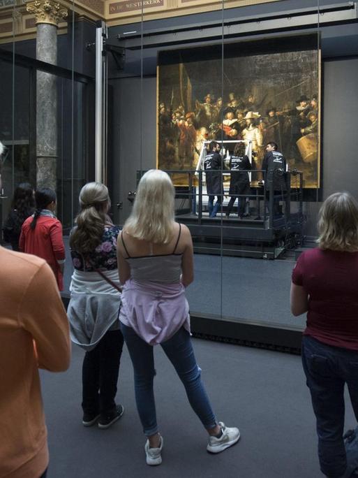 Zuschauer betrachten Rembrandts "Nachtwache", während das berühmte Bild gerade im Rijksmuseum in Amsterdam restauriert wird.