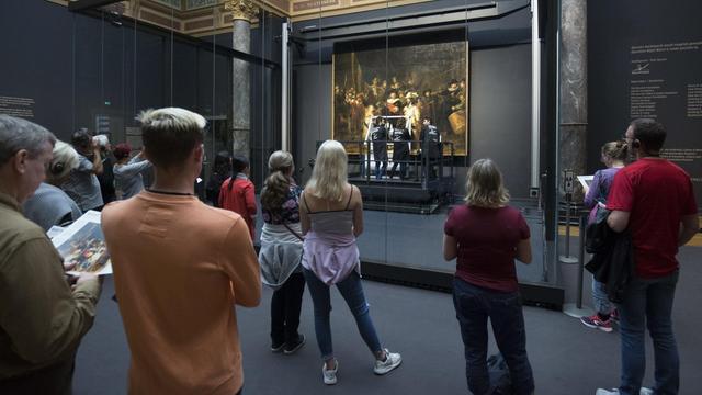 Zuschauer betrachten Rembrandts "Nachtwache", während das berühmte Bild gerade im Rijksmuseum in Amsterdam restauriert wird.