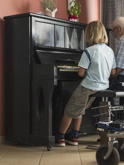 Ein Großvater gibt seinem Enkel eine Klavierstunde.