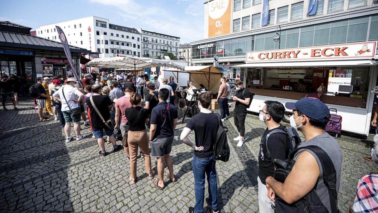 Menschen warten in der Schlange eines mobilen Impfteams auf dem Hermannplatzin Berlin.