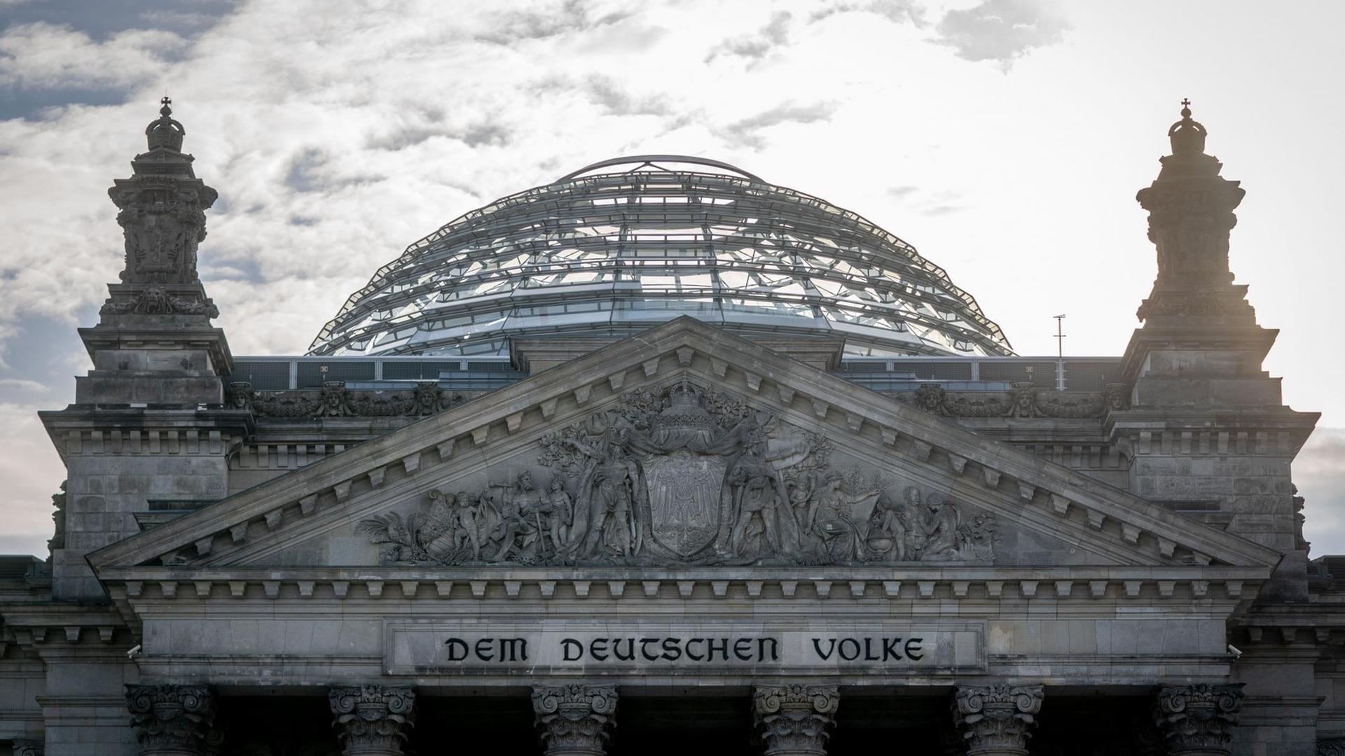 Die Sonne steht an einem Morgen hinter dem Reichstagsgebäude mit dem Bundestag in Berlin