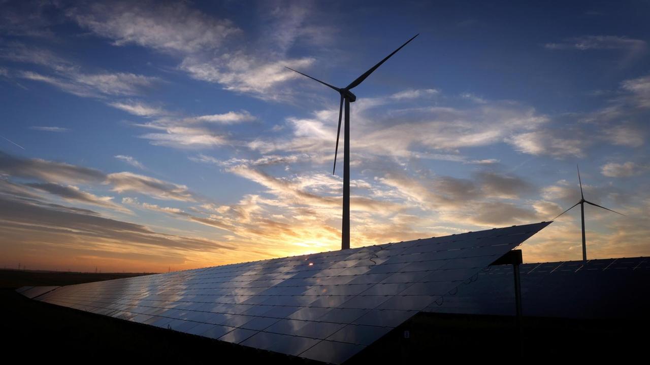 Windräder stehen hinter den Solarzellen einer Solarkraftanlage beim Sonnenuntergang Windräder stehen hinter den Solarzellen einer Solarkraftanlage beim Sonnenuntergang
